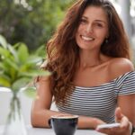 Justine happy-woman-sitting-coffee-shop-min