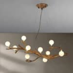Plafonnier original branche d’arbre et boules de lumière sur fond gris.