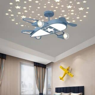 Plafonnier chambre enfant avion suspendu de couleur bleu avec une partie en-dessous qui éclaire. Des étoiles sont projetées sur le plafond. Les murs de la pièce sont beiges et les rideaux marron.