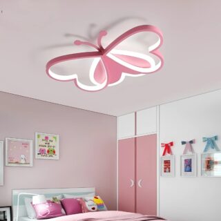 Plafonnier chambre enfant en forme de papillon rose avec une bande bande LED sur le contour. Il est fixé dans une chambre avec un lit blanc et une literie rose. Le lur de droite est blanc avec des portes de placards roses.