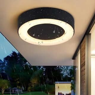 Plafonnier extérieur noir et rond avec un anneau lumineux à LED. Il est fixé sur une terrasse et des gouttelettes d'eau sous visibles devant le luminaire.