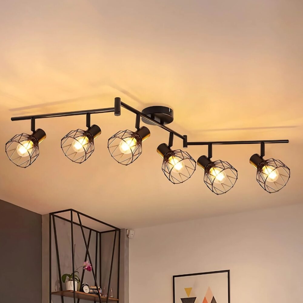 Plafonnier spots orientables avec bras articulés composé de 6 spots. Chaque spot est muni d'un abat-jour en forme de cage métallique ajourée et d'une ampoule allumée. Fixé dans une pièce avec une étagère en fond.