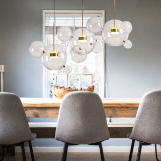 Suspension lumineuse au-dessus d'une table à manger, avec 3 boules transparentes et petites sphères en verre accrochées a chacune