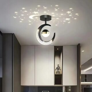 Plafonnier LED en forme de lune avec projections d'étoiles au plafond. Le luminaire est noir avec une lune et à l'intérieur la boule lumineuse qui diffuse les étoiles. Fixé dans une pièce avec de placards sur les murs.