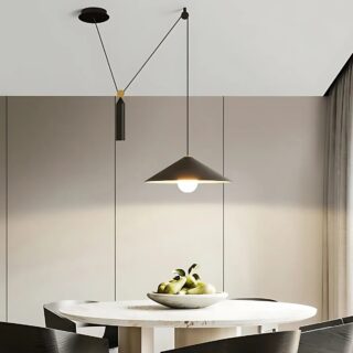 Plafonnier déporté avec hauteur ajustable de couleur noire. Son abat-jour est de forme conique, le câble est noir relié avec un point au plafond puis un balancier cylindrique noir. L'ampoule est allumée. Il est fixé au-dessus d'une table ovale beige avec des sièges noirs.