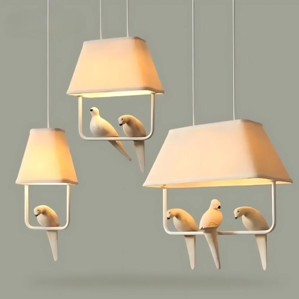 Luminaire plafonnier rétro avec oiseaux perchés. Sur l'image, trois luminaires sont suspendus de gauche à droite : 1 oiseau, 2 oiseaux et trois oiseaux. Les luminaires sont de couleur beige avec un abat-jour en tissu et les oiseaux perchés sur une barre en dessous. Les ampoules sont allumées. Sur fond gris.