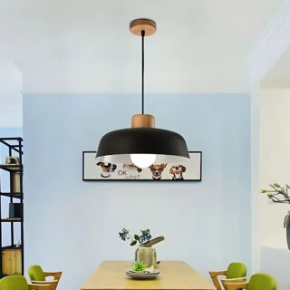 Luminaire plafonnier suspendu de style nordique de couleur noire avec une ampoule allumée et il est fixé au-dessus d'une table en bois rectangulaire. Il y a une plante au centre et le mur en face est bleu ciel. Les chaises sont vertes.
