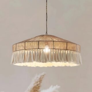 Plafonnier bohème en corde de chanvre et pompons avec l'ampoule au centre allumée. Une pampa en dessous et un fond beige.