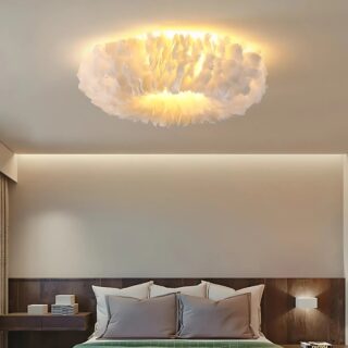Plafonnier chambre adulte ciel de plumes en forme d'anneau avec une lumière jaune au centre. Fixé au plafond d'une chambre avec un lit double. La literie est blanche et grise. La tête de lit est marron.