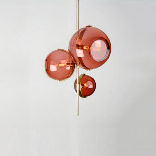 Lustre plafonnier au design d'exception composé de trois globes en verre rouge alignés verticalement sur une structure métallique dorée.