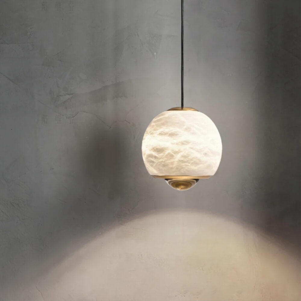Lustre plafonnier en marbre sculpté beige suspendu de forme sphérique sur fond gris.