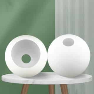 Abat-jour en forme de globe en deux exemplaires disposés sur une table basse blanche