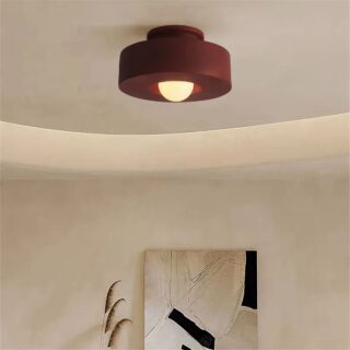Plafonnier en résine couleur terracotta avec ampoule apparente, fixé au plafond d’une pièce.